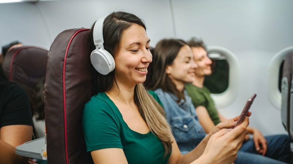 woman with wireless headphones listening to music on an airplane